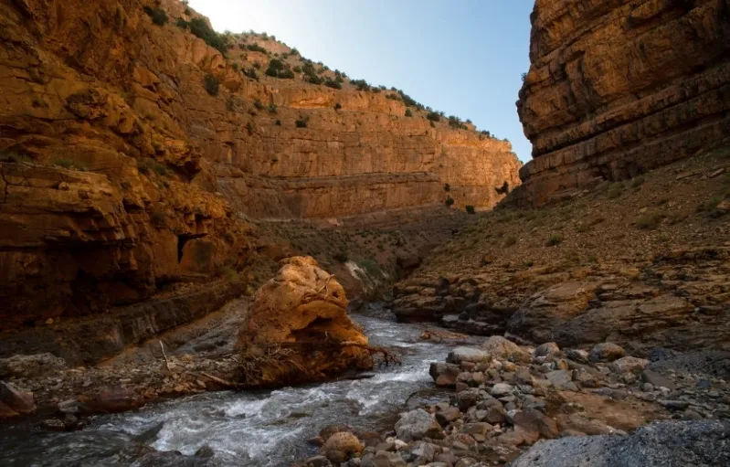 A river flows through a canyon surrounded by the rugged peaks of the Atlas Mountains in Morocco.