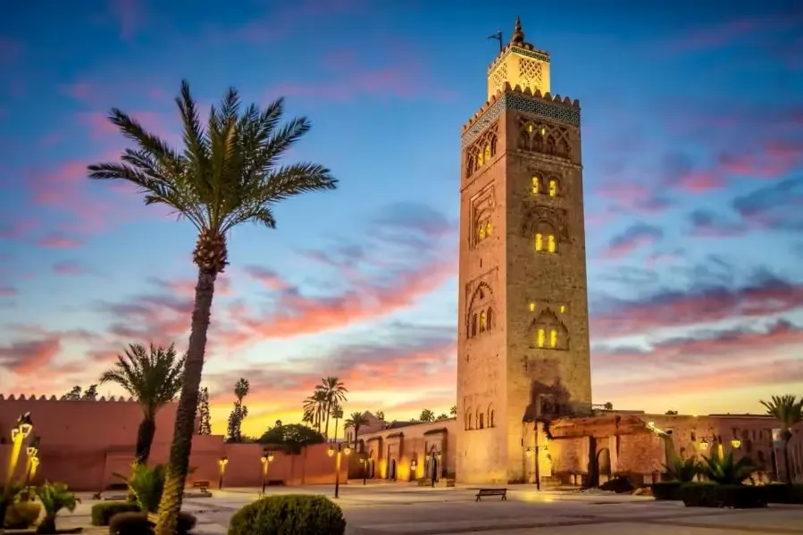 Sunset view of Marrakech's clock tower, highlighting its architecture against a vibrant sky, ideal for Marrakech tours.
