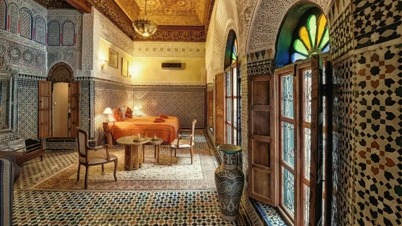 Interior of a room in Fes, Morocco, featuring a bed and a window with natural light streaming in.
