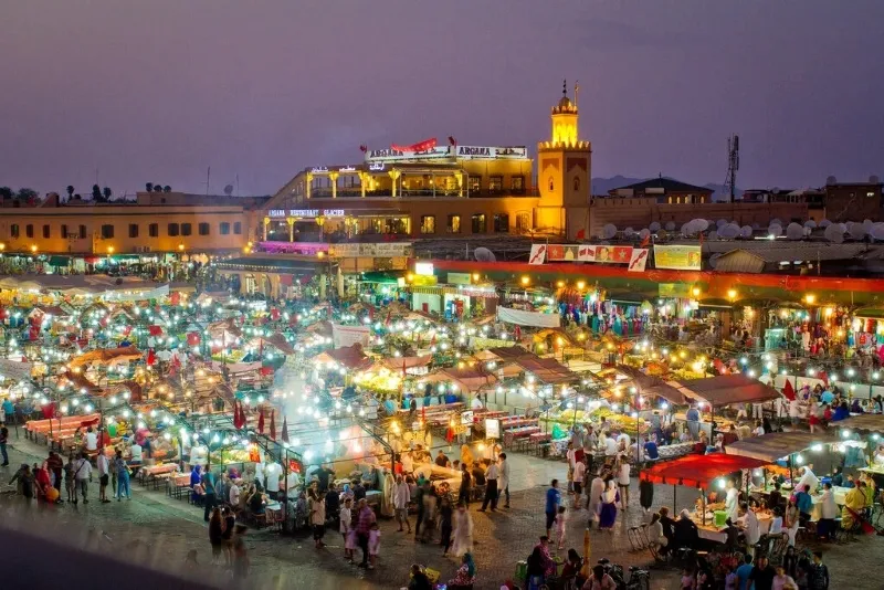 Night view of Marrakech, showcasing illuminated attractions and vibrant city life under a starry sky.